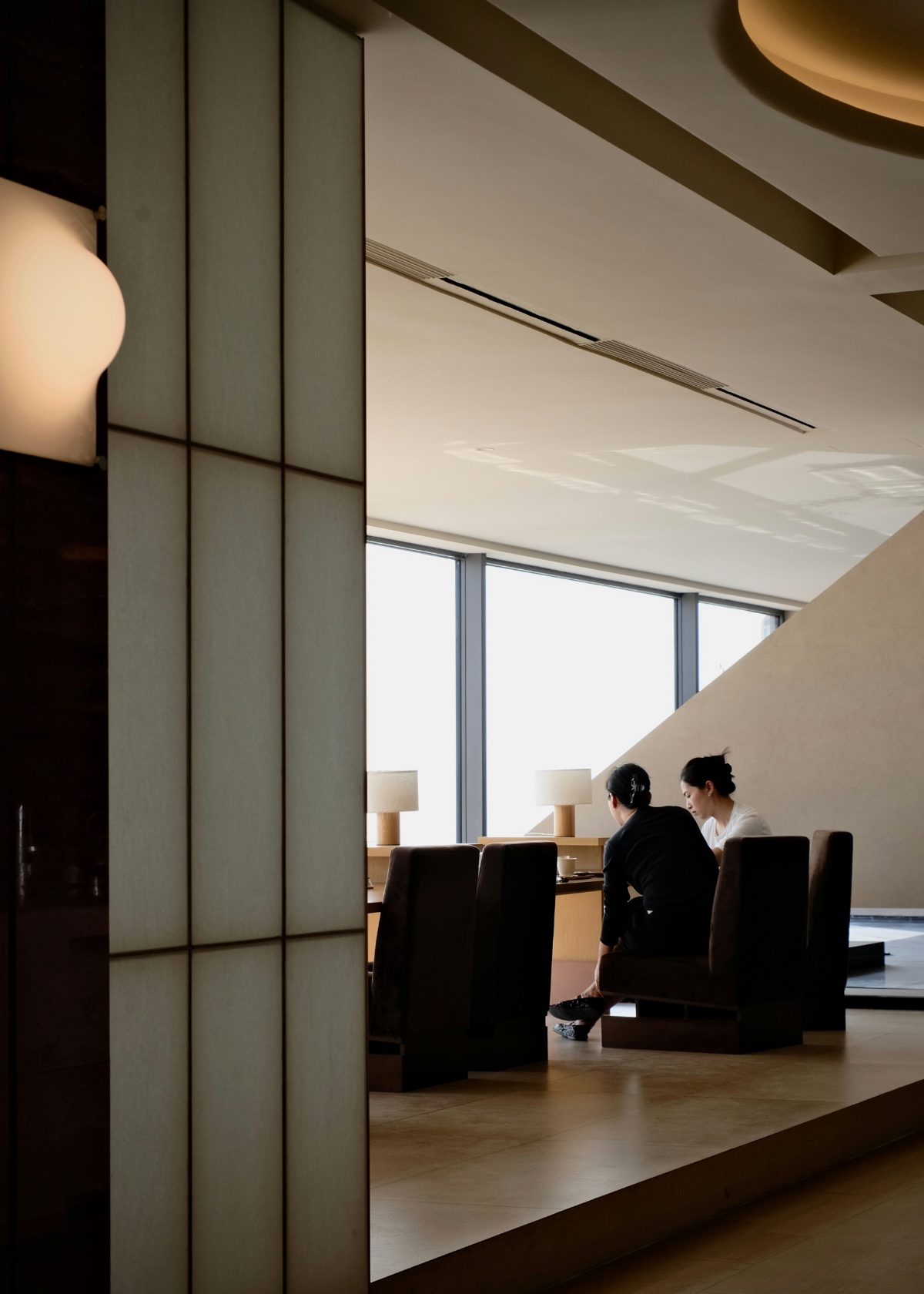 Two colleagues working at a window table in a quiet lounge